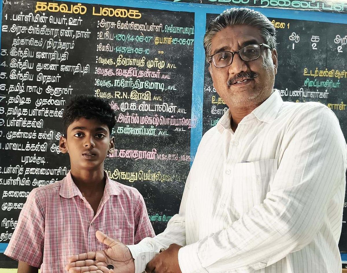 மாணவனை பாராட்டும் தலைமை ஆசிரியர்